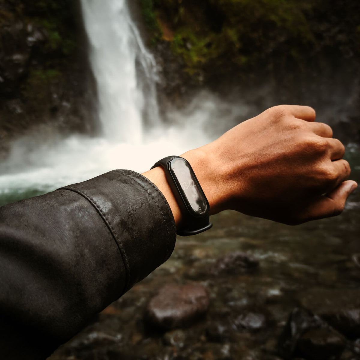 Smart band on wrist in front of a waterfall