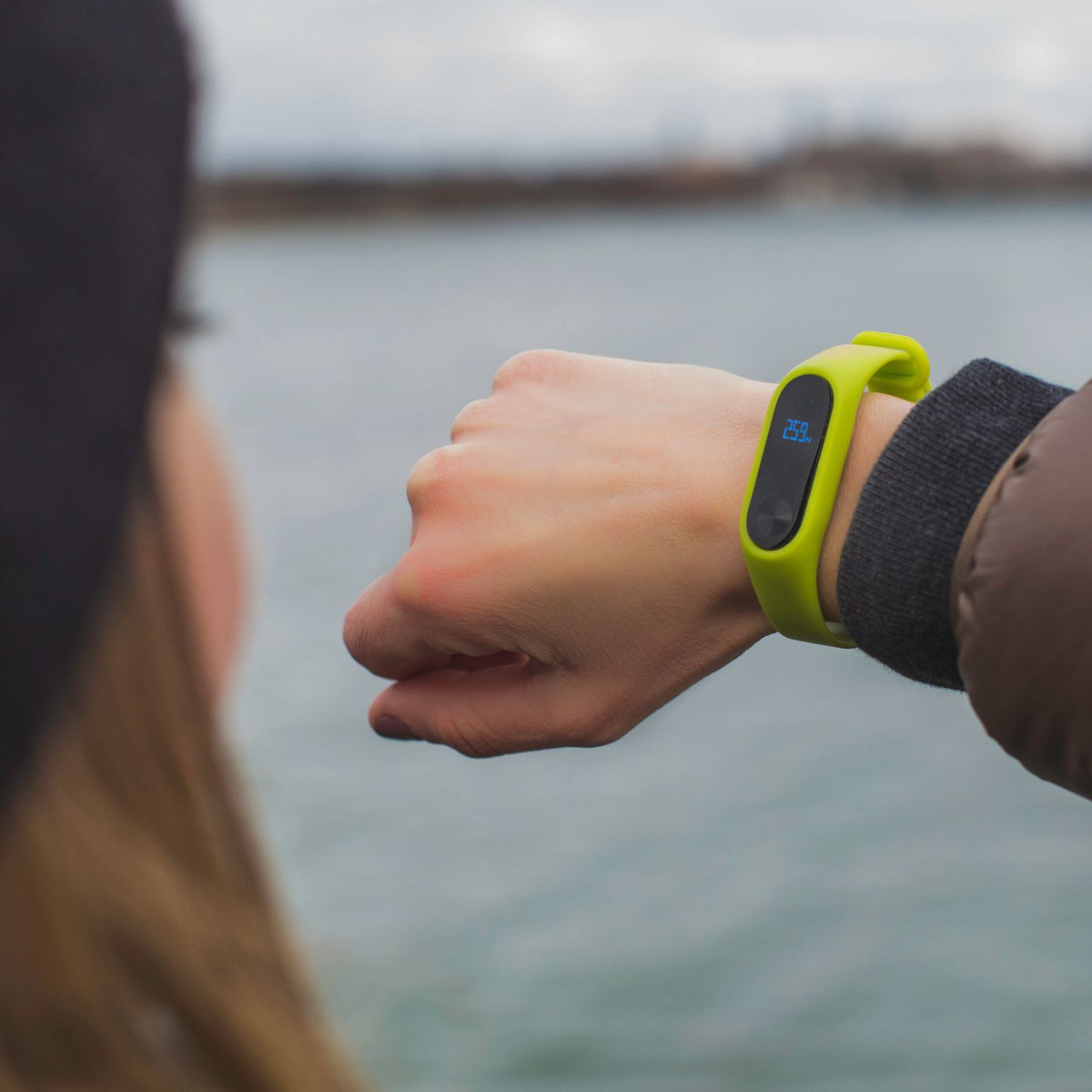 Woman checking her fitness band by a lake