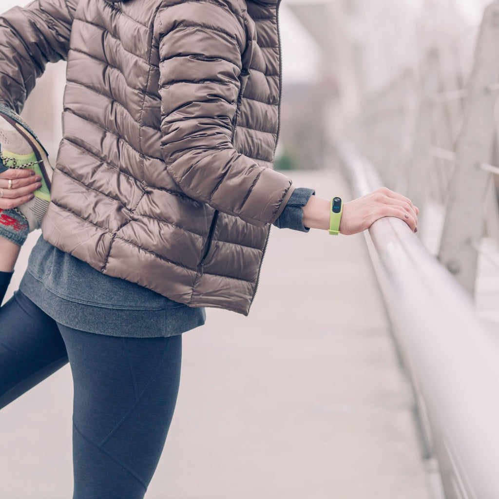Woman stretching outdoors wearing a fitness band