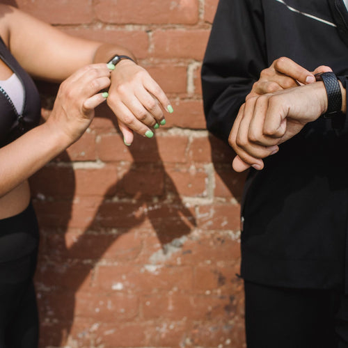Two people checking their fitness trackers outdoors