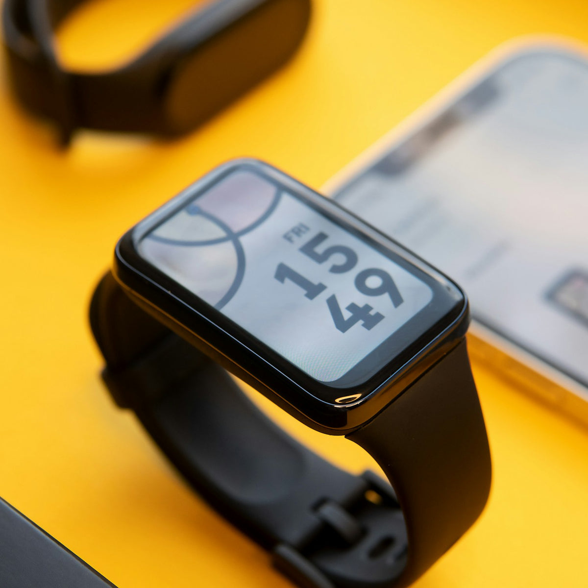 Rectangular AMOLED fitness band on a yellow desk